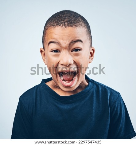 Listen to me. Studio shot of a cute little boy playfully screaming against a grey background.