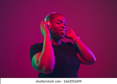 Listen To Music. African-american Young Woman's Portrait On Purple Background. Beautiful Model In Wireless Headphones. Concept Of Emotions, Facial Expression, Sales, Ad, Inclusion. Copyspace.