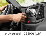 Listening to radio while driving. Man turning volume button on vehicle audio in car, closeup