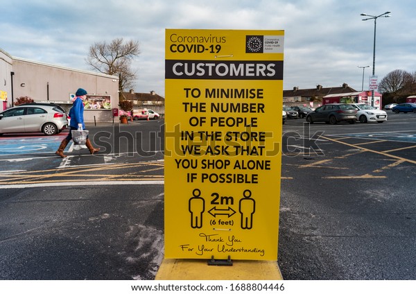 Listowel, Ireland - 30th March 2020: \
Covid-19 Sign at entrance to supermarket car park warning customers\
of social distancing rules of 2\
meters