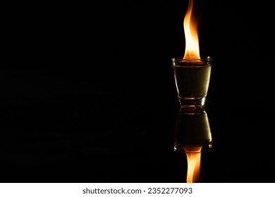 Lit candle in glass container with copy space on black background. Flame, fire, colour and light concept.