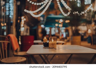 Lit Up Candle At An Outdoor Table Of A Restaurant In Winter, Cosy Atmosphere, Selective Focus, Bokeh.