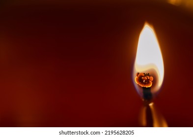 A Lit Candle Wick With Red Background