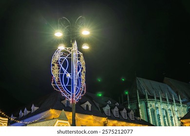 A lit up Christmas tree with a clock on top of it. The scene is set in a city at night