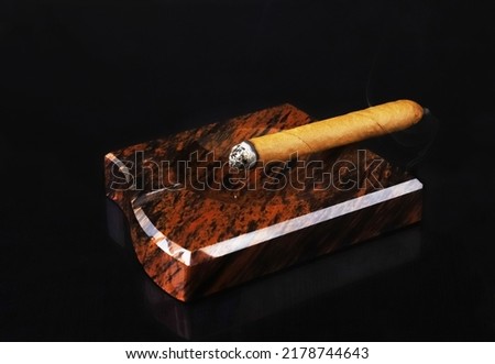 A lit cigar in an ashtray under dark lighting. Close-up