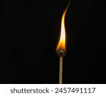 Lit match with curved flame on black background