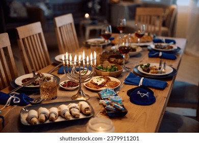 Lit menorah on dining table prepared for family meal on Hanukkah.