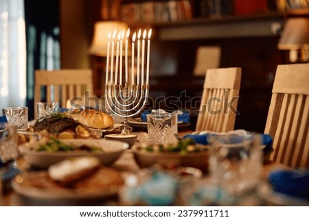 Lit menorah and traditional Jewish food on dining table on Hanukkah. 
