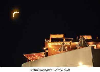 A Lit Rooftop Cafe With A Moonlit Night Sky In The Background