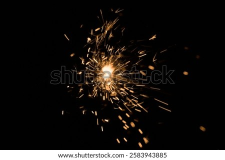 A lit sparkler agains a black background