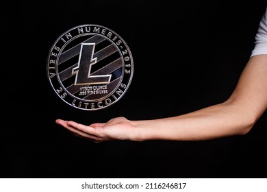 Litecoin coin and a man's hand on a black background. A symbol of technology and a new means of currency settlement