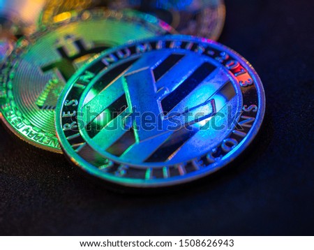 Litecoin laying on dark table with beautiful colourful reflections in the coin and powerful color which resembles technology.