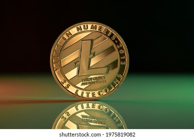 Litecoin LTC cryptocurrency physical coin placed on reflective surface and lit with green and red lights