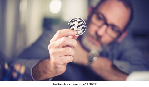 Litecoins - one Litecoin cryptocurrency in hand of a casual businessman wondering what the future is