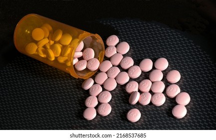 Lithium Pills Poured From An Orange  Prescription Medication Bottle Onto A Black And Grey Surface.