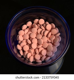 Lithium Pills In A Small Blue Glass Bowl Placed Upon A Dark Glass Surface.