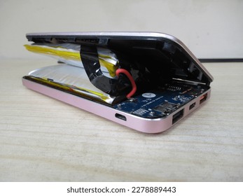 Lithium-ion battery on powerbank, which has expanded. Broken battery, Lithium polymer battery swollen dangerous to explode and catch on fire, Damaged power bank.