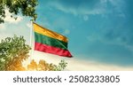 Lithuania national flag waving in the sky behind the tree. The flag blowing with beautiful sunlight. Lithuania national flag for independence day.