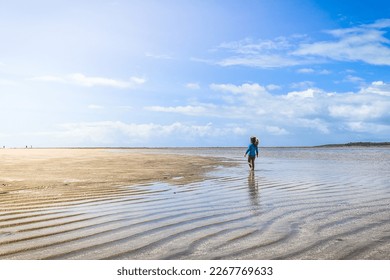 Litlle girl walking on low tide beach at Moreré Bahia Brazil