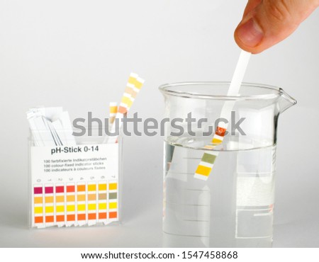 Litmus strips for measurement of acidity. Beaker with water. Water tester. PH test.