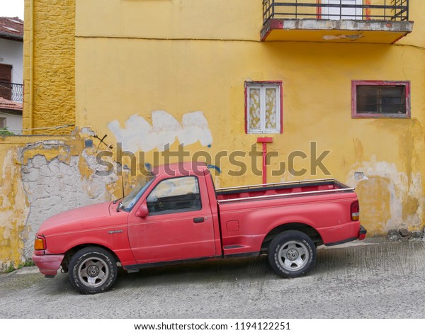 LITOCHORO, GREECE -  JULY 24.\
2018,Old vintage red Ford ranger  pickup truck  in front of old\
yellow house, Litochoro July  24. 2018. Olympus region, Macedonia,\
Greece