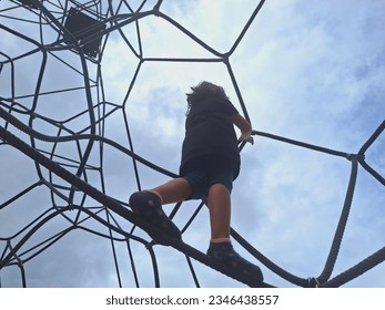 A littel girl climbing rope nets at the playground on sunny day. - Powered by Shutterstock