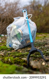 A litter picker and a full bag of rubbish that has been collected from a beach clean picking up discarded rubbish and litter. Litter pick, environmental, beach clean concept - Shutterstock ID 2099953291
