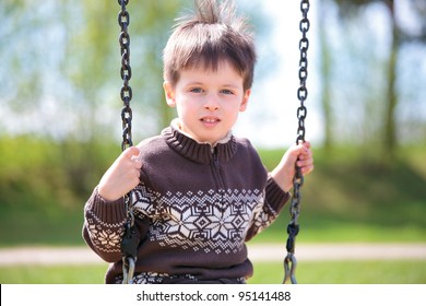 Little 3 Year Old Boy On Swing In Playground Outdoors