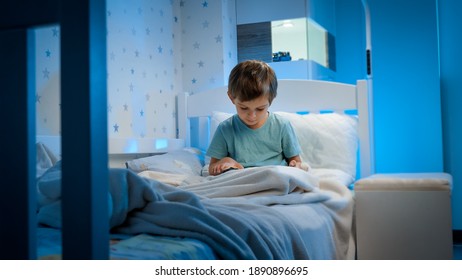 Little 5 Years Old Boy Using And Playing On Tablet Computer Before Going To Sleep At Night. Child With Gadget At Evening.