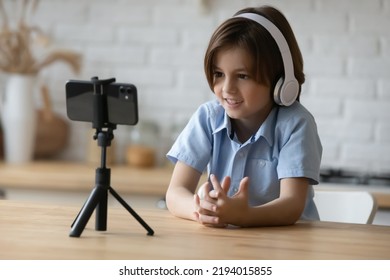 Little 6s boy social media blogger in headphones makes speech record new videovlog use smartphone camera on tripod. Video call event, on-line teacher, young gen modern tech usage, fun, e study