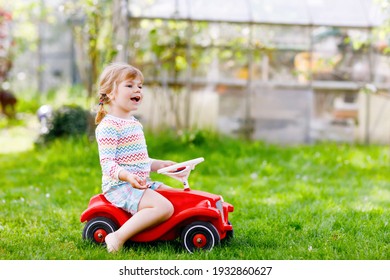 Little Active Adorable Toddler Girl Driving Toy Car And Having Fun With Playing, Outdoors. Gorgeous Happy Healthy Child Enjoying Warm Summer Day. Smiling Stunning Kid In Gaden