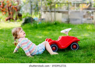 Little Active Adorable Toddler Girl Falling Down From Toy Car, Having Pain And Crying, Outdoors. Upset Child On Summer Day. Injured Hurt Kid In Gaden