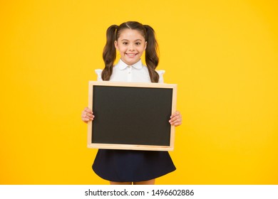 Little Ad Maker. Little Schoolchild Holding Blackboard On Yellow Background. Little Child With Black-board For School Advertisement. Little Girl With Empty Chalkboard For Your Text, Copy Space.