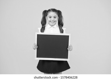 Little Ad Maker. Little Schoolchild Holding Blackboard On Yellow Background. Little Child With Black-board For School Advertisement. Little Girl With Empty Chalkboard For Your Text, Copy Space.