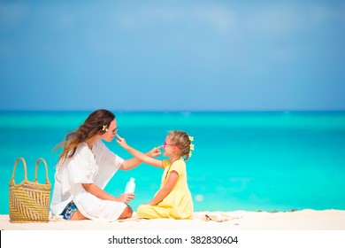 Little adorable girl applying sun cream to her mother nose