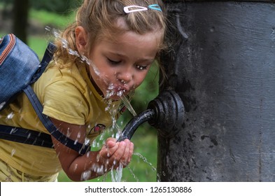 Little Adorable Girl Child Drinks Water From The Drinking Fountain 