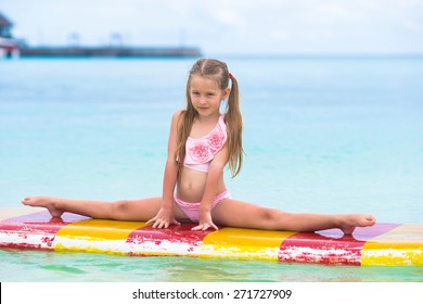 Little adorable girl on a surfboard in the turquoise sea
