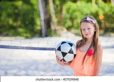 Little adorable girl playing voleyball on beach with ball