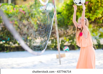 Little adorable girl playing voleyball on beach with ball. Sporty family enjoy beach game outdoors