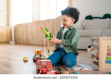 little african american boy playing toys sitting on warm floor in modern living room. Baby development. Small tower. Learning creative concept - Powered by Shutterstock