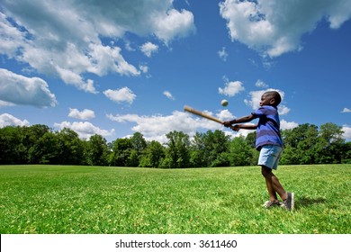 Little African American boy playing baseball in a sunny field on a beautiful summer day. - Powered by Shutterstock