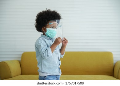 A Little African American Boy Wearing Face Mask And Face Shield At Home