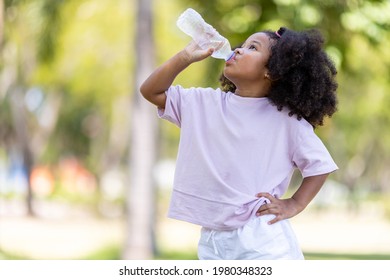 Little African American curly-haired girl concept holding plastic bottles and looking and drinking water on a hot day in the garden. - Powered by Shutterstock