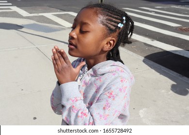 Little African American Girl Praying, Dreaming, Wishing Outside On A City Street. 