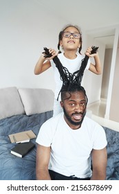 Little African American Girl Pulling Hair Of Father On Bed