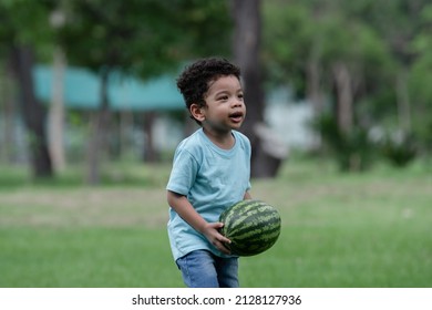 Little African American Kid Boy Carrying A Big Watermelon In The Farm. Child Having Fun Helping Family To Harvest Watermelons In The Garden.