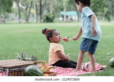 Little African American Kids Picnic And Playing In The Park. Little Cute Girl Crying And Boy Consoling His Friend With Giving Her A Piece Of Watermelon. Friendship Of Diverse Ethnicity Children