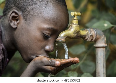 Маленький африканский мальчик пьет здоровую чистую воду из водопровода