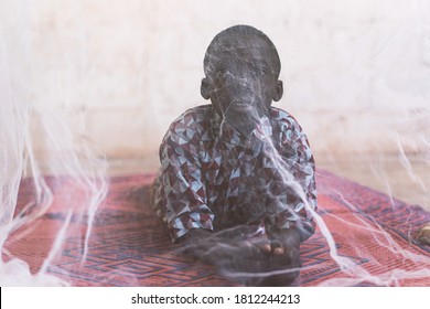 Little African Boy With Mosquito Net For Protection Against Malaria