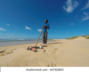 Little african boy playing in the sand with his wire car